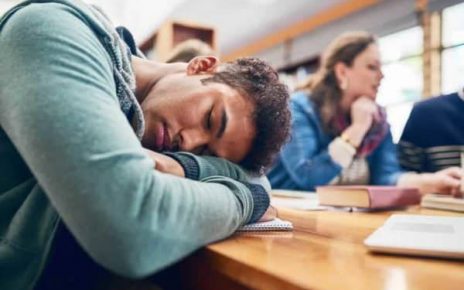 Stock image of student sleeping in class with his head down.